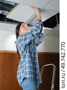 female electrician fixing ceiling lighting. Стоковое фото, агентство Ingram Publishing / Фотобанк Лори