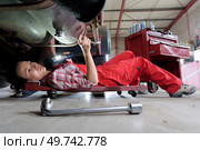 female mechanic underneath a car. Стоковое фото, агентство Ingram Publishing / Фотобанк Лори