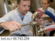 serviceman operating industrial water purification or filtration equipment. Стоковое фото, агентство Ingram Publishing / Фотобанк Лори