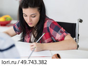 invalid girl writing in a notepad on wheelchair. Стоковое фото, агентство Ingram Publishing / Фотобанк Лори