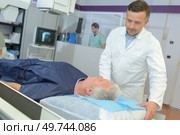 radiologist adjusting xray machine over man. Стоковое фото, агентство Ingram Publishing / Фотобанк Лори