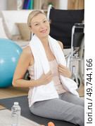 woman sits next to a wheelchair on blue yoga mat. Стоковое фото, агентство Ingram Publishing / Фотобанк Лори