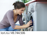woman crouched down to use washing machine. Стоковое фото, агентство Ingram Publishing / Фотобанк Лори