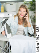 disabled woman ironing clothes and talking by phone. Стоковое фото, агентство Ingram Publishing / Фотобанк Лори