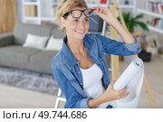 woman unrolling a wall paper on the wall. Стоковое фото, агентство Ingram Publishing / Фотобанк Лори