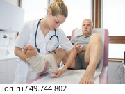 young nurse bandaging mans foot in clinic. Стоковое фото, агентство Ingram Publishing / Фотобанк Лори