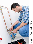 Plumber making adjustments to the heating system. Стоковое фото, агентство Ingram Publishing / Фотобанк Лори