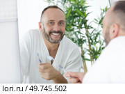 mature man reflected in mirror holding toothbrush. Стоковое фото, агентство Ingram Publishing / Фотобанк Лори