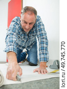 a young man fitting linoleum. Стоковое фото, агентство Ingram Publishing / Фотобанк Лори