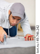 a young man is stapling an insulating layer to floor. Стоковое фото, агентство Ingram Publishing / Фотобанк Лори