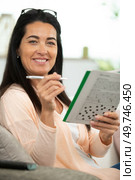 young beautiful woman doing crosswords in room. Стоковое фото, агентство Ingram Publishing / Фотобанк Лори