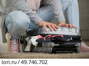 cropped view of woman cramming closed her suitcase. Стоковое фото, агентство Ingram Publishing / Фотобанк Лори