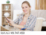 woman assembling furniture looking on tablet for instructions. Стоковое фото, агентство Ingram Publishing / Фотобанк Лори