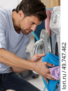 young man loading the laundry into the washing machine. Стоковое фото, агентство Ingram Publishing / Фотобанк Лори