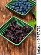 Bowl of fresh blueberries and dried cranberries on rustic wooden table.. Fresh and dried berries on wooden table. Стоковое фото, агентство Ingram Publishing / Фотобанк Лори