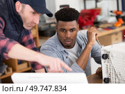 apprentice repairing an appliance under supervision. Стоковое фото, агентство Ingram Publishing / Фотобанк Лори