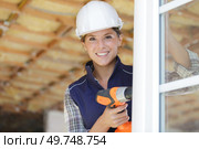 female builder using cordless drill on pvc window. Стоковое фото, агентство Ingram Publishing / Фотобанк Лори