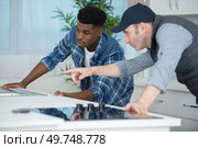carpenter and apprentice installing fitted kitchen. Стоковое фото, агентство Ingram Publishing / Фотобанк Лори
