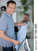smiling man ironing cloth in domestic kitchen at home. Стоковое фото, агентство Ingram Publishing / Фотобанк Лори
