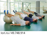 Four men with legs raised on aerobic balls. Стоковое фото, агентство Ingram Publishing / Фотобанк Лори