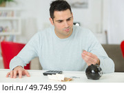 man looking at his penny before putting in piggybank. Стоковое фото, агентство Ingram Publishing / Фотобанк Лори