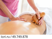 From above of crop anonymous massage therapist massaging with wooden therapy tool back of client lying on table during osteopathy session in clinic. Crop masseur doing massage to client with wooden therapy tool in physiotherapy clinic. Стоковое фото, агентство Ingram Publishing / Фотобанк Лори