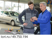 auto mechanic teacher and trainee performing tests at mechanic school. Стоковое фото, агентство Ingram Publishing / Фотобанк Лори