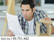 a carpenter reading furniture manual. Стоковое фото, агентство Ingram Publishing / Фотобанк Лори
