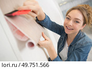 happy woman unrolling a wall paper on the wall. Стоковое фото, агентство Ingram Publishing / Фотобанк Лори