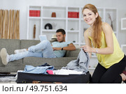 woman packing while boyfriend relaxes. Стоковое фото, агентство Ingram Publishing / Фотобанк Лори