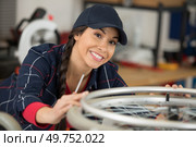 mechanic servicewoman adjusting bicycle wheel in workshop. Стоковое фото, агентство Ingram Publishing / Фотобанк Лори