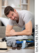 man tries to packing all the necessary clothes for travel. Стоковое фото, агентство Ingram Publishing / Фотобанк Лори