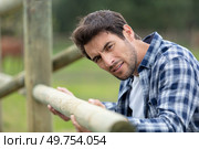 man assembling wood fence in a ranch. Стоковое фото, агентство Ingram Publishing / Фотобанк Лори