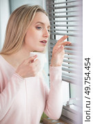 beautiful young woman looks out through blinds. Стоковое фото, агентство Ingram Publishing / Фотобанк Лори
