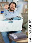 young man prefers to watch tv than doing laundry. Стоковое фото, агентство Ingram Publishing / Фотобанк Лори
