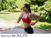 In a sunny park, a determined young woman in red sports bra and black shorts exemplifies an active, athletic lifestyle filled with energy and focus, showcasing strength and endurance. A woman is jogging in a park on a sunny day, dressed in sportswear, showcasing her dedication to an active lifestyle. Стоковое фото, агентство Ingram Publishing / Фотобанк Лори