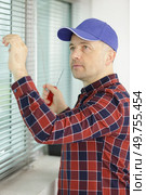male contractor installing window blinds. Стоковое фото, агентство Ingram Publishing / Фотобанк Лори