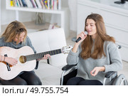2 teen girls doing music together one is disabled. Стоковое фото, агентство Ingram Publishing / Фотобанк Лори