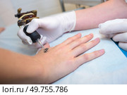 a hand applying a tattoo. Стоковое фото, агентство Ingram Publishing / Фотобанк Лори
