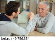 aged father and his handsome son competing in arm wrestling. Стоковое фото, агентство Ingram Publishing / Фотобанк Лори