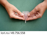 Hands holding menstrual cup over violet background, eco friendly and zero waste solution. Menstrual cap over violet background. Стоковое фото, агентство Ingram Publishing / Фотобанк Лори