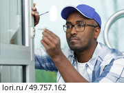 man fixing the door handle with screwdriver. Стоковое фото, агентство Ingram Publishing / Фотобанк Лори