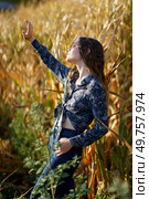 A captivating and enchanting portrait of a young woman dressed in a stylish outfit, gracefully posing amidst the vibrant golden cornfields, beautifully merging the elements of nature and fashion. An Elegant Portrait Captured in a Beautiful Cornfield During the Enchanting Golden Hour. Стоковое фото, агентство Ingram Publishing / Фотобанк Лори