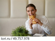 Cute elegant beauty businesswoman biting a sandwich sitting in a modern cafeteria. Cute businesswoman biting a sandwich in a modern cafeteria. Стоковое фото, агентство Ingram Publishing / Фотобанк Лори