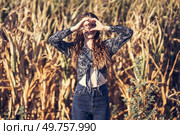 In a beautiful and vibrant golden field, a lively young woman effortlessly forms a heart shape using her hands, which wonderfully captures her infectious happiness and profound sense of contentment. A Young Woman is Playfully Posing in a Beautiful Golden Field, Capturing the Essence of Summer. Стоковое фото, агентство Ingram Publishing / Фотобанк Лори