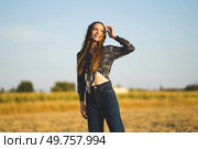 A smiling young woman joyfully poses in a sunlit field, showcasing her trendy outfit while embodying a carefree spirit amidst the stunning beauty of nature, creating a picturesque scene. A Joyful Young Woman Enjoys a Beautiful Sunny Field with Her Unique Sense of Style. Стоковое фото, агентство Ingram Publishing / Фотобанк Лори
