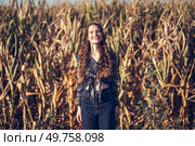 A joyful young woman beams brightly as she stands amidst a lush golden cornfield, perfectly capturing the essence of rural beauty along with the blissful, carefree moments that we truly cherish. A Joyful Young Woman Standing in a Beautiful Cornfield During a Scenic Sunset Hour. Стоковое фото, агентство Ingram Publishing / Фотобанк Лори