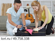 a happy couple closing luggage. Стоковое фото, агентство Ingram Publishing / Фотобанк Лори