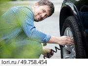 smiling man inflate rubber tires car. Стоковое фото, агентство Ingram Publishing / Фотобанк Лори