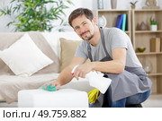a man spraying sofa house service. Стоковое фото, агентство Ingram Publishing / Фотобанк Лори